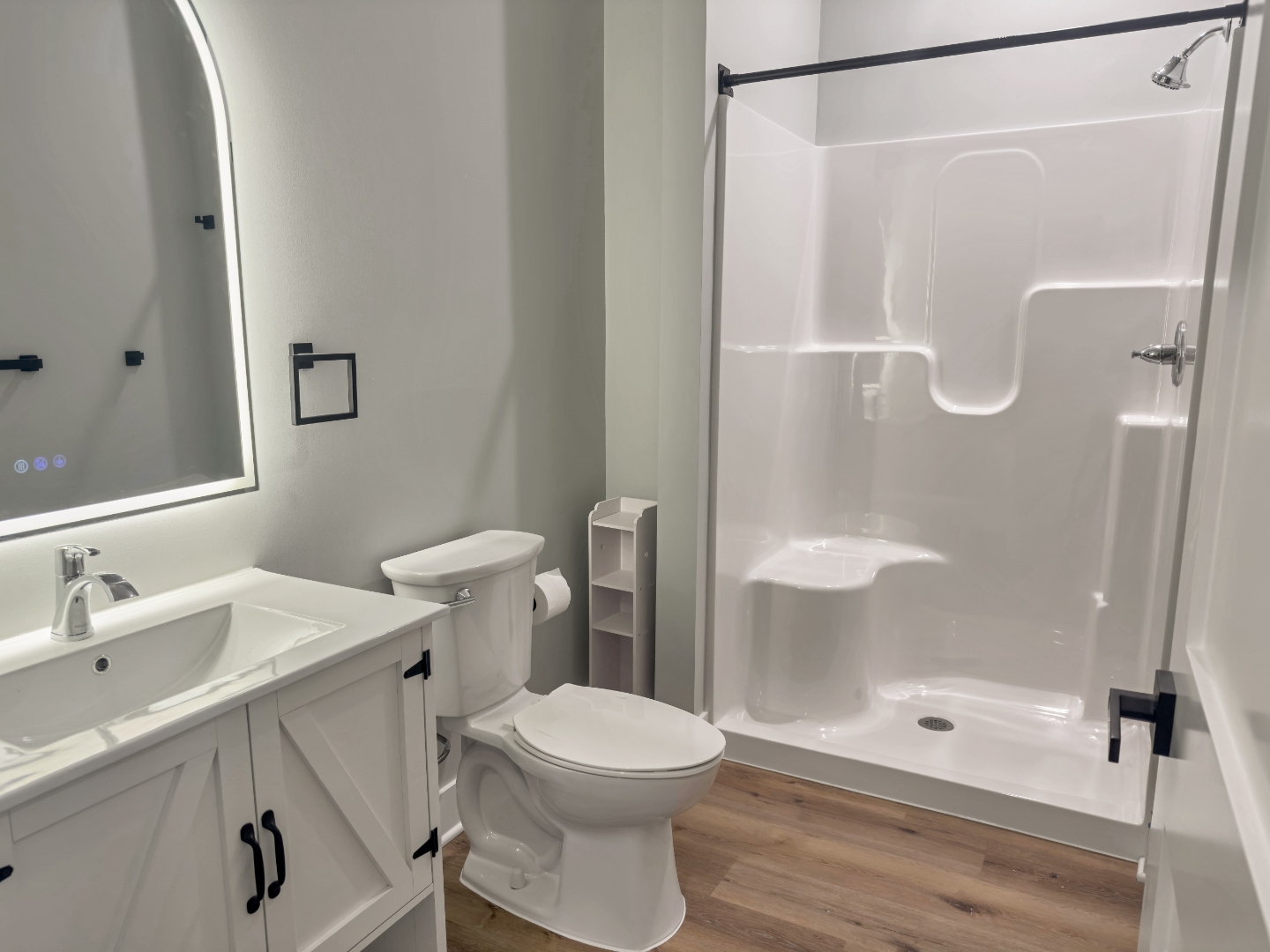 Lopez Lofts bathroom — LED mirror vanity, walk-in shower with built-in seat, and matte black fixtures