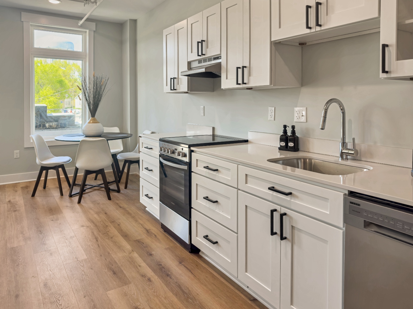 Lopez Lofts kitchen — white shaker cabinets, quartz countertops, stainless appliances, and dining area